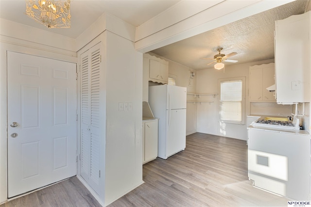 kitchen featuring white appliances, ceiling fan with notable chandelier, light hardwood / wood-style flooring, and white cabinets