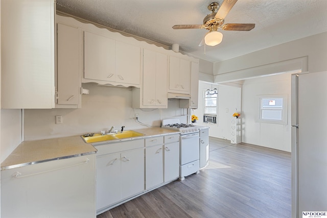 kitchen with white cabinetry, sink, a textured ceiling, and white appliances