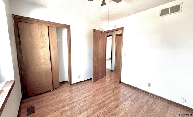 unfurnished bedroom with a textured ceiling, light hardwood / wood-style floors, and ceiling fan