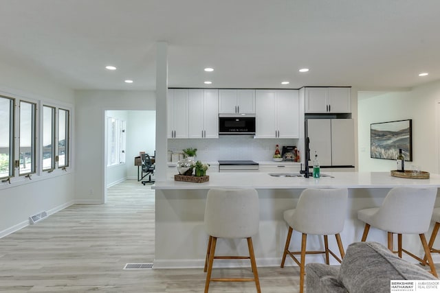 kitchen featuring sink, tasteful backsplash, white fridge, white cabinets, and stove