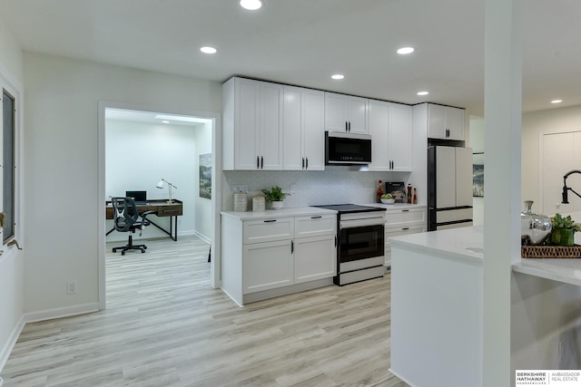 kitchen featuring electric stove, tasteful backsplash, white cabinetry, white refrigerator, and light hardwood / wood-style flooring