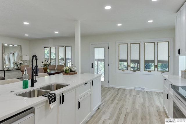 kitchen with sink, dishwasher, white cabinets, and light wood-type flooring