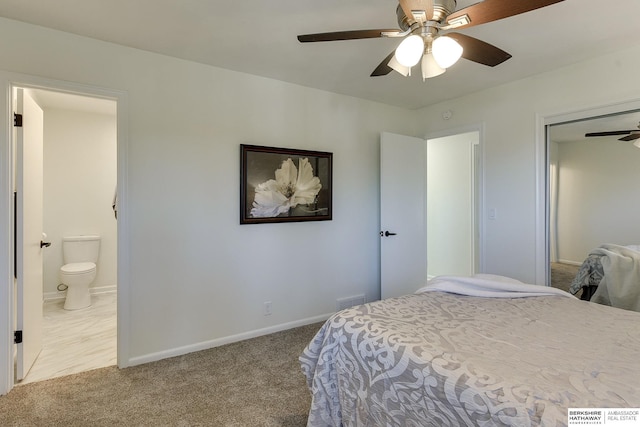 bedroom featuring ceiling fan, light colored carpet, and ensuite bath