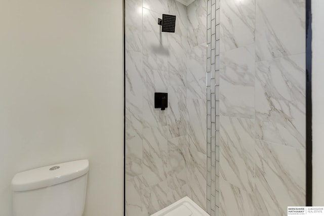 bathroom with a tile shower and toilet