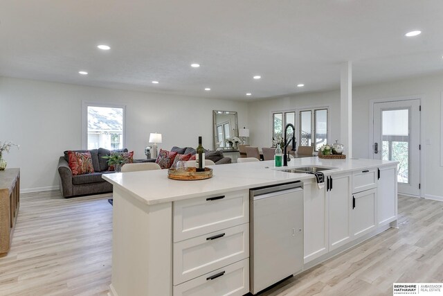 kitchen featuring sink, light hardwood / wood-style floors, white cabinets, a center island with sink, and stainless steel dishwasher