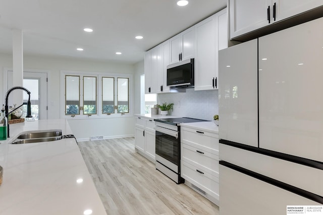 kitchen with sink, light hardwood / wood-style flooring, stainless steel appliances, light stone countertops, and white cabinets