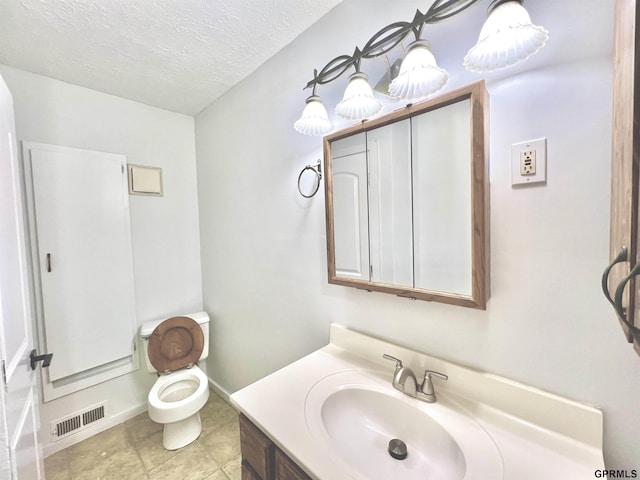 bathroom featuring vanity, a textured ceiling, and toilet