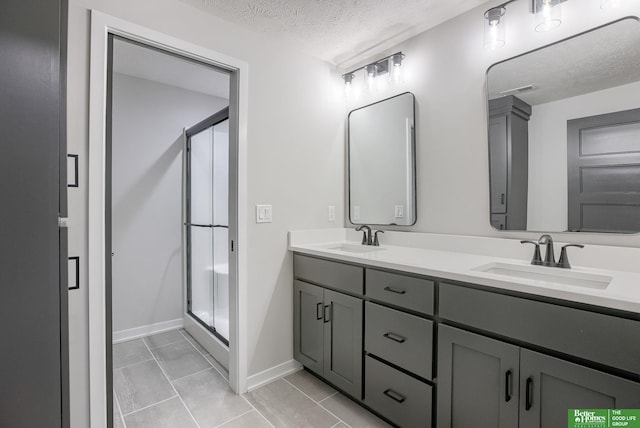 bathroom featuring vanity, tile patterned floors, a textured ceiling, and walk in shower