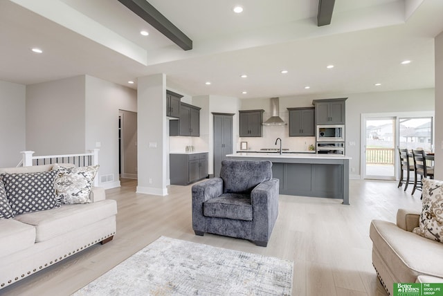 living room with sink, beam ceiling, and light hardwood / wood-style floors