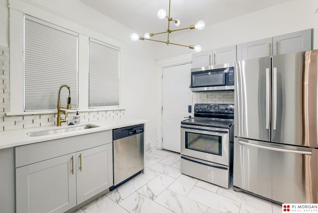 kitchen featuring gray cabinets, appliances with stainless steel finishes, sink, and backsplash