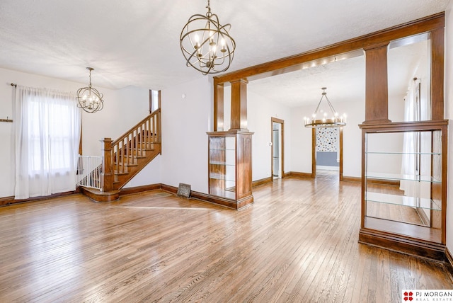 interior space featuring hardwood / wood-style flooring, a textured ceiling, a notable chandelier, and decorative columns