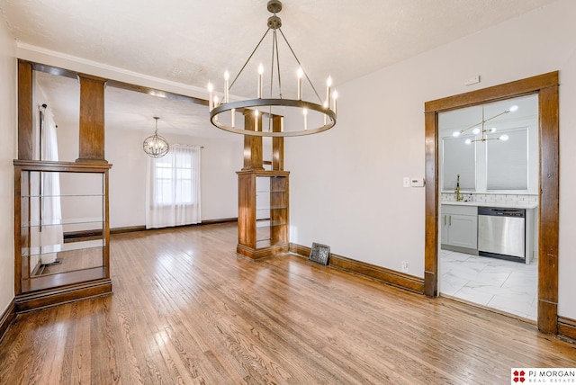 unfurnished dining area featuring sink, hardwood / wood-style floors, and a notable chandelier