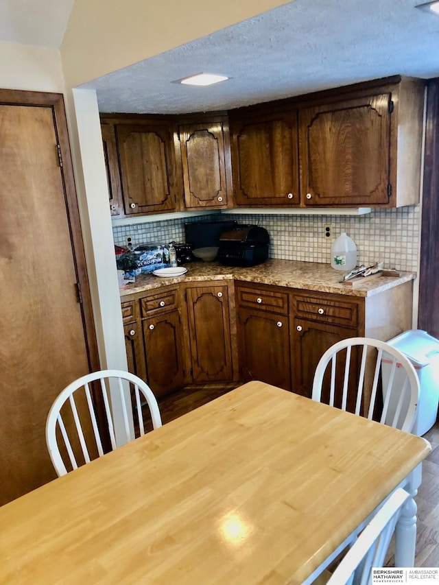 kitchen featuring dark brown cabinetry, decorative backsplash, and dark wood-type flooring