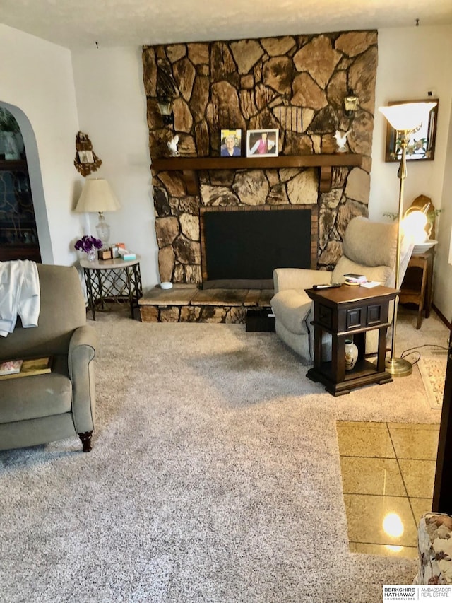 carpeted living room with a stone fireplace