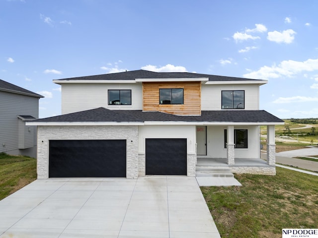 view of front of property with a porch, a garage, and a front lawn