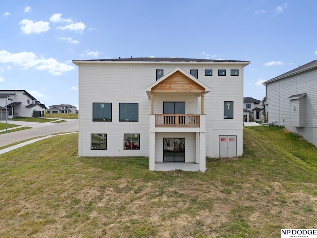 rear view of house with a lawn and a balcony