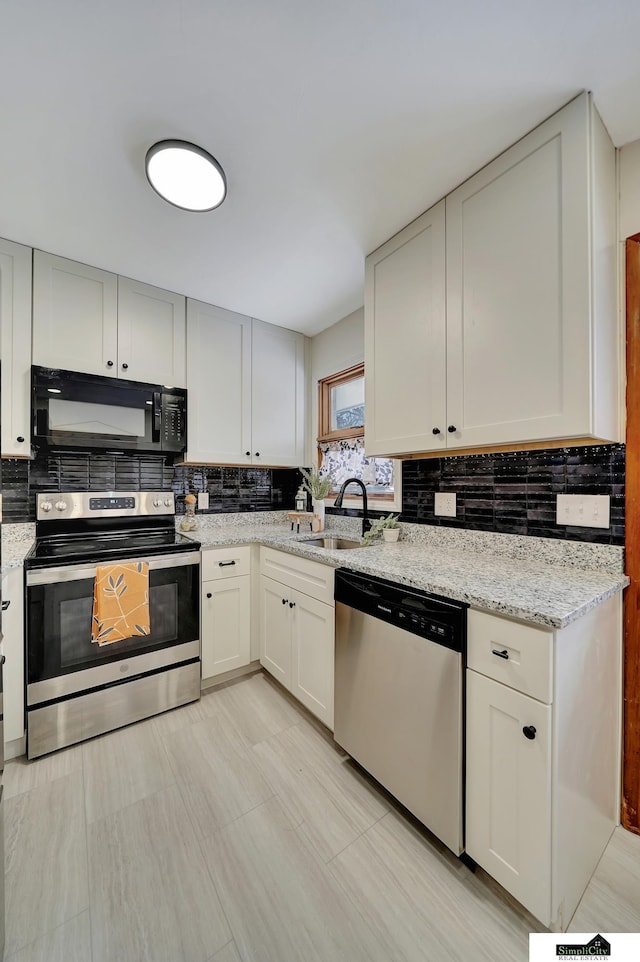 kitchen featuring white cabinetry, appliances with stainless steel finishes, sink, and light stone counters