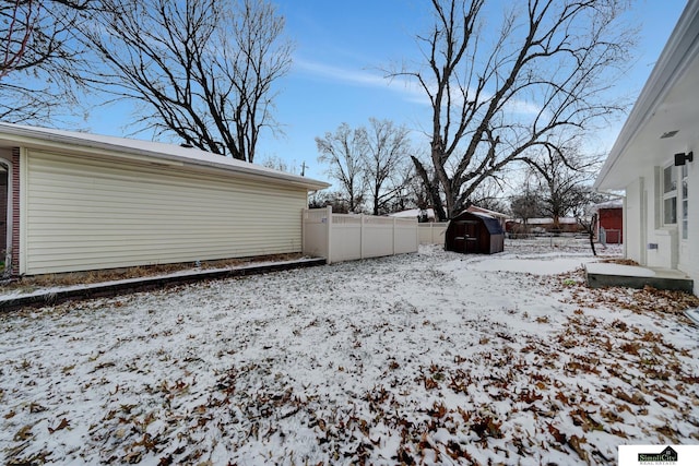 yard covered in snow featuring a storage shed