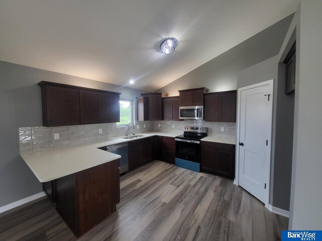 kitchen featuring sink, appliances with stainless steel finishes, light hardwood / wood-style floors, decorative backsplash, and vaulted ceiling