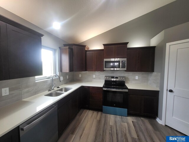 kitchen featuring wood-type flooring, appliances with stainless steel finishes, sink, and decorative backsplash