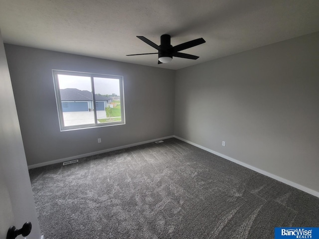 empty room featuring ceiling fan and dark colored carpet