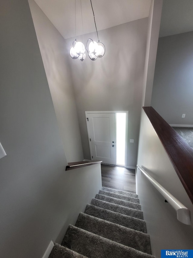 stairs featuring wood-type flooring and a notable chandelier