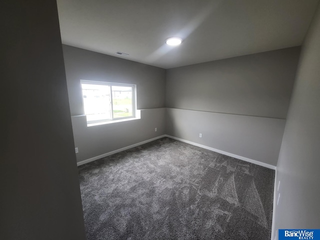 spare room with dark carpet