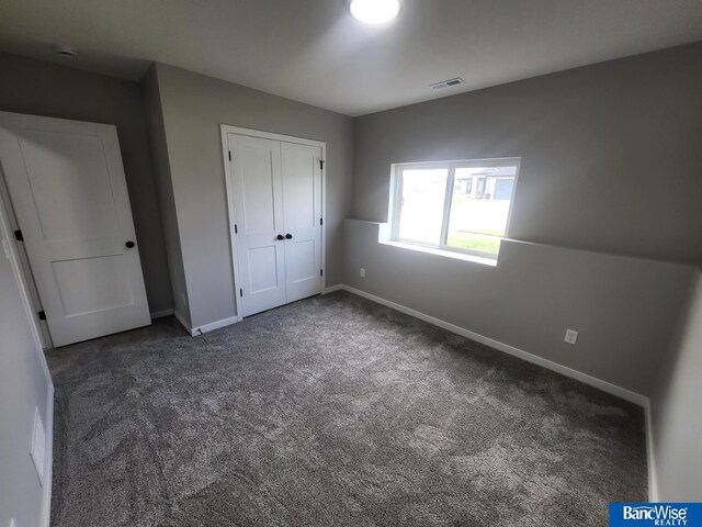 unfurnished bedroom featuring dark colored carpet and a closet