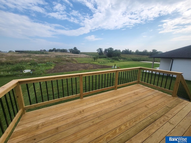 wooden terrace with a rural view and a lawn