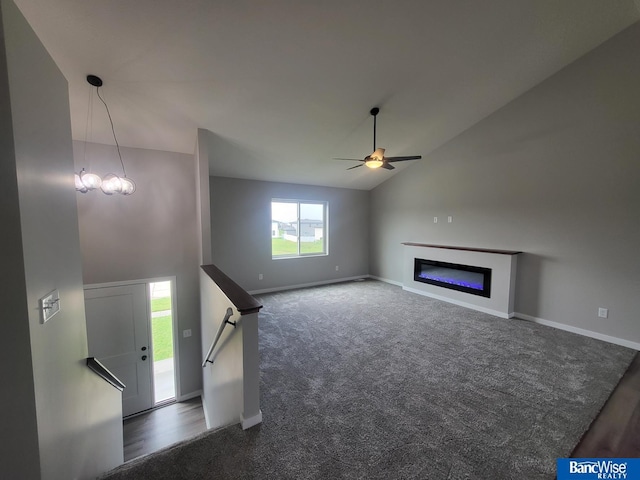 unfurnished living room with vaulted ceiling, dark carpet, and ceiling fan