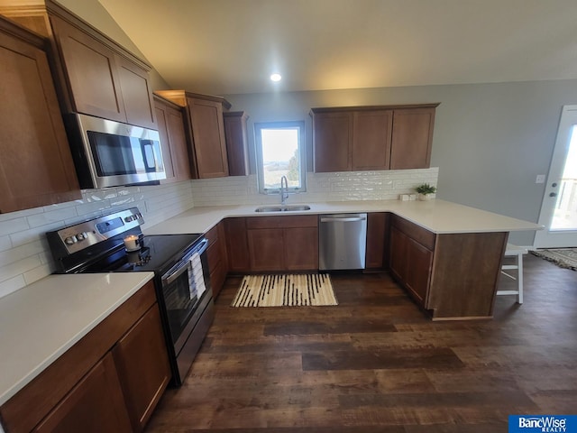 kitchen featuring stainless steel appliances, light countertops, a sink, and a peninsula