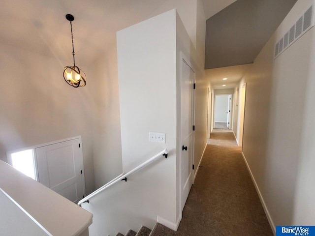 corridor featuring dark colored carpet, visible vents, and baseboards