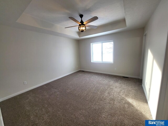 spare room featuring carpet floors, ceiling fan, and a tray ceiling