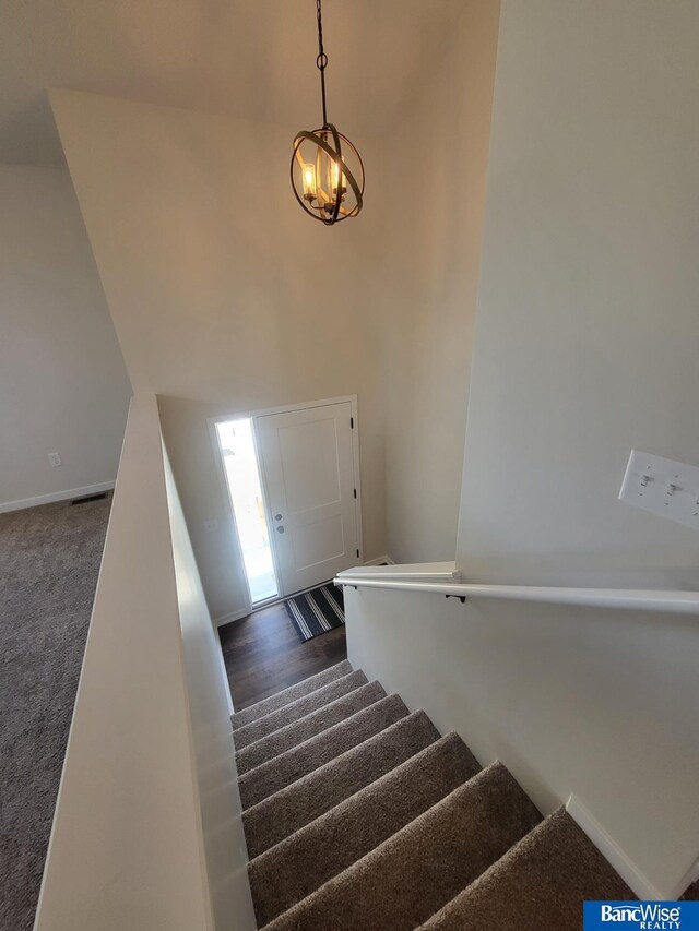 stairway with a high ceiling, carpet, visible vents, and baseboards