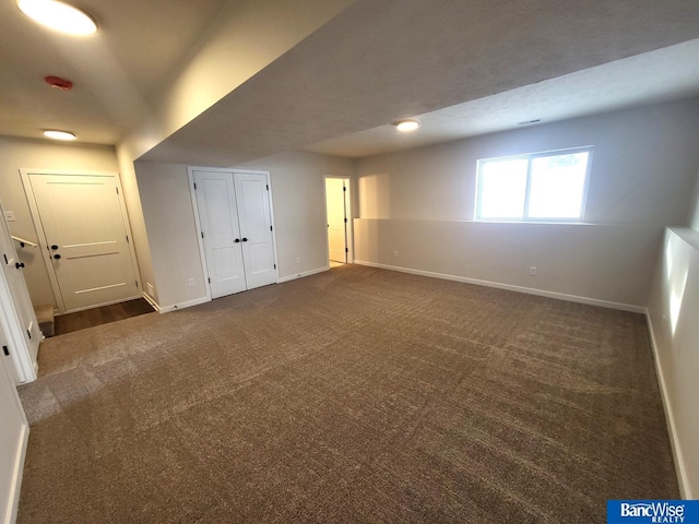 unfurnished bedroom with dark colored carpet, a closet, and baseboards