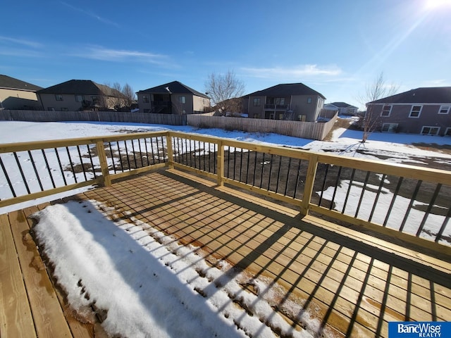 snow covered deck featuring a residential view and fence