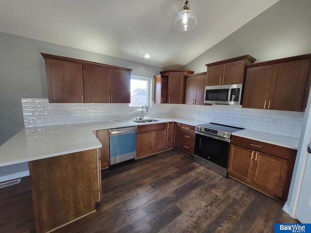 kitchen with stainless steel appliances, dark wood-type flooring, a sink, hanging light fixtures, and light countertops