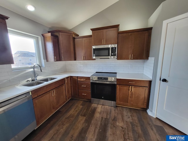 kitchen featuring stainless steel appliances, dark wood-type flooring, a sink, vaulted ceiling, and light countertops