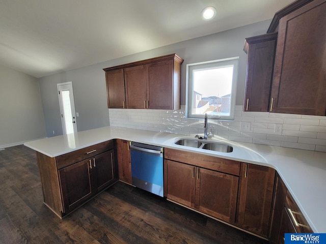 kitchen featuring dark wood-type flooring, a peninsula, light countertops, stainless steel dishwasher, and a sink