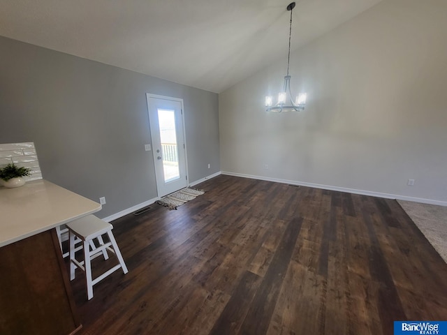 unfurnished dining area featuring lofted ceiling, an inviting chandelier, baseboards, and dark wood-type flooring