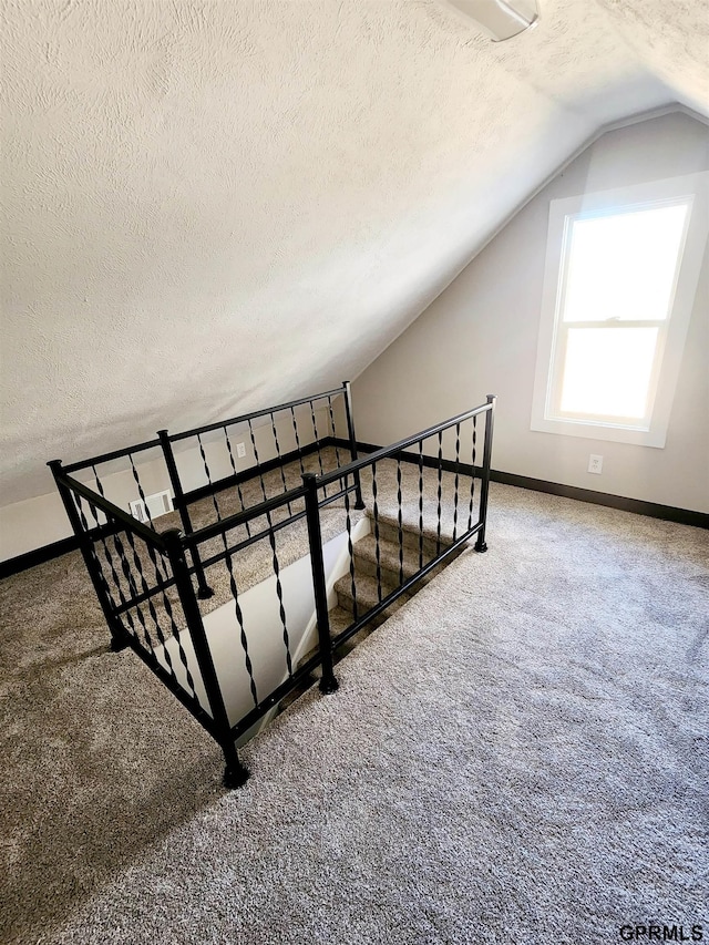 stairway featuring carpet flooring and a textured ceiling