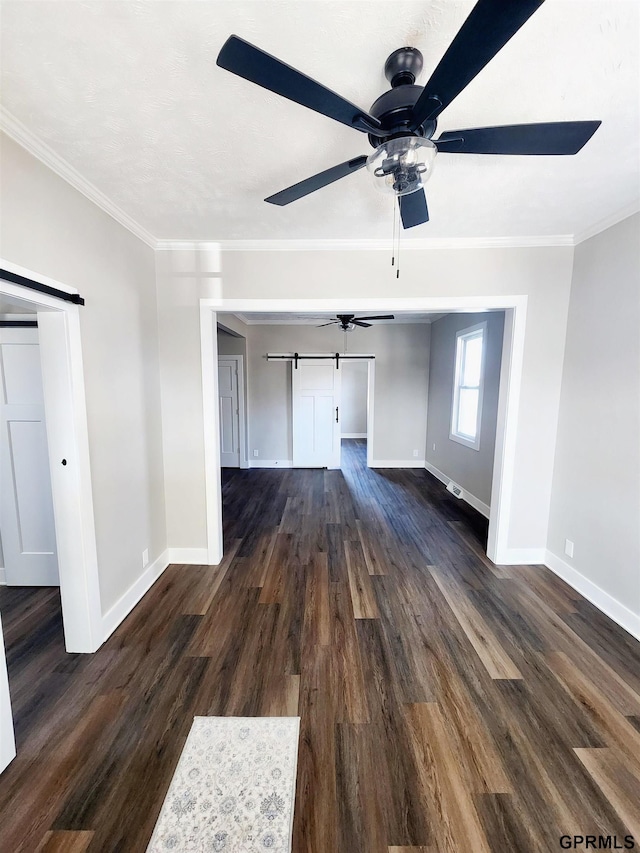 unfurnished living room with crown molding, a barn door, and dark hardwood / wood-style flooring