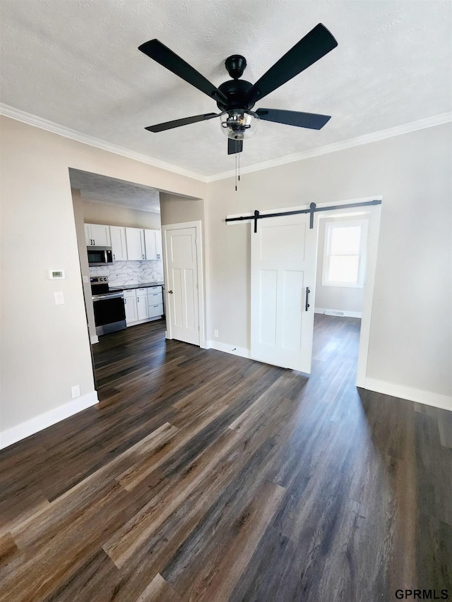 unfurnished living room with ornamental molding, ceiling fan, a barn door, dark wood-type flooring, and a textured ceiling