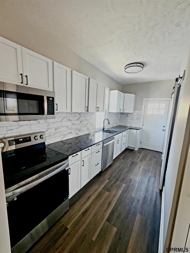 kitchen featuring a textured ceiling, stainless steel appliances, a barn door, and white cabinets