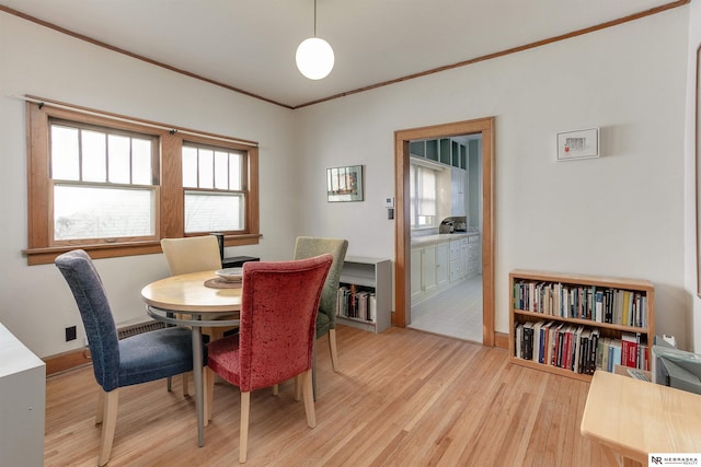 dining space featuring crown molding, light wood-style flooring, and baseboards