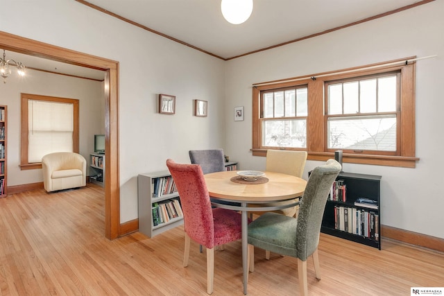 dining area featuring ornamental molding, a chandelier, light wood-style flooring, and baseboards