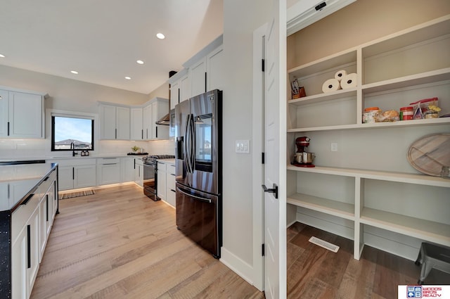 kitchen featuring appliances with stainless steel finishes, white cabinets, backsplash, and light hardwood / wood-style flooring