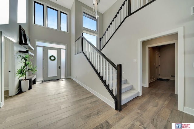 foyer with a towering ceiling and light hardwood / wood-style floors