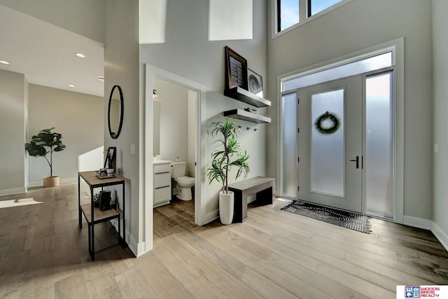 foyer entrance featuring a towering ceiling and light hardwood / wood-style flooring