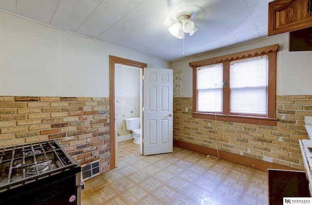 kitchen featuring ceiling fan, brick wall, gas stove, and light parquet floors